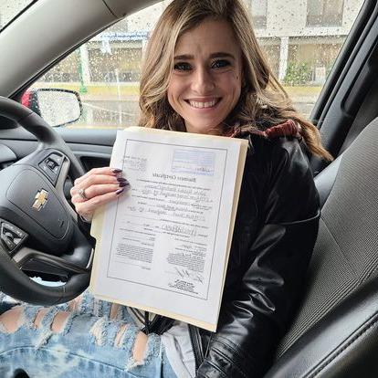 young women in a car holding an official document